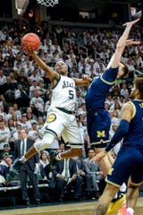 On the left, Michigan State's Cassius Winston shoots for Colin Castleton's Michigan defenseman on Saturday, March 9, 2019, at the East Lansing Breslin Center.