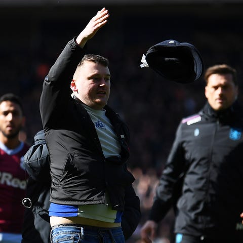 A fan is escorted off the pitch after striking...