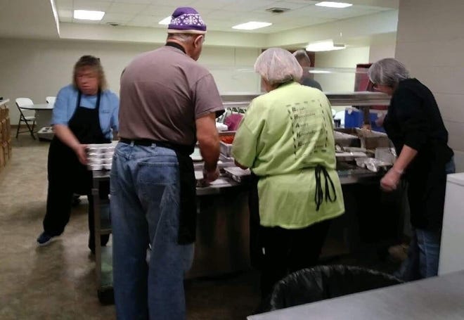 Meals on Wheels workers portion out and package meals daily at The Gathering Place senior center for local recipients.