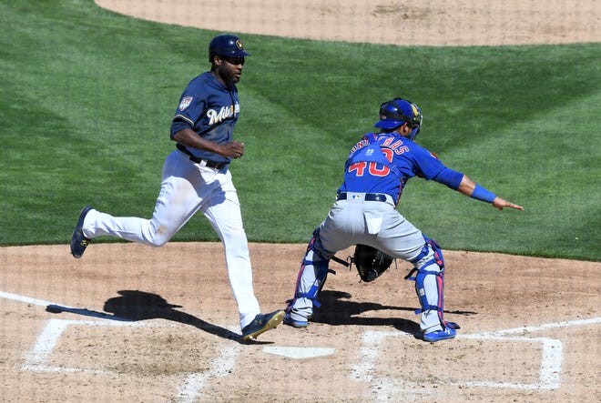 PHOENIX, ARIZONA - MARCH 10: Lorenzo Cain #6 of the Milwaukee Brewers scores on a double by Yasmani Grandal #10 during the third inning of a spring training game as Willson Contreras #40 of the Chicago Cubs waits for the throw from right field at Maryvale Baseball Park on March 10, 2019 in Phoenix, Arizona. (Photo by Norm Hall/Getty Images)