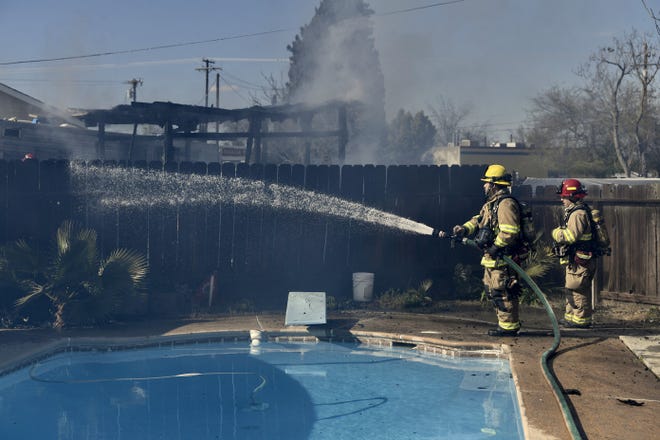 Visalia firefighters at the scene of a shed fire near Santa Fe Street and Houston Avenue on Monday, March 11, 2019.  A fence near the shed was charred.