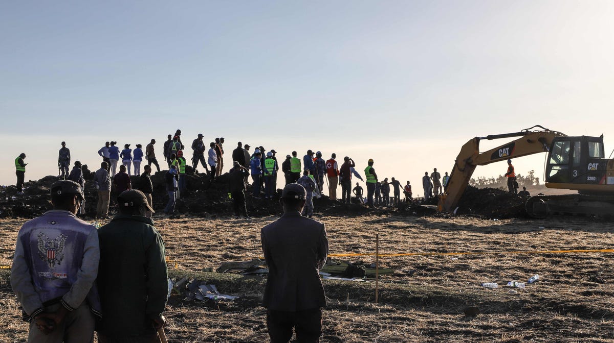 People watch workers at the crash site  of a Nairobi-bound Ethiopian Airlines flight near Bishoftu, a town some 60 kilometres southeast of Addis Ababa, Ethiopia, on March 10, 2019. A Nairobi-bound Ethiopian Airlines Boeing crashed minutes after takeoff from Addis Ababa on March 10, killing all eight crew and 149 passengers on board.
