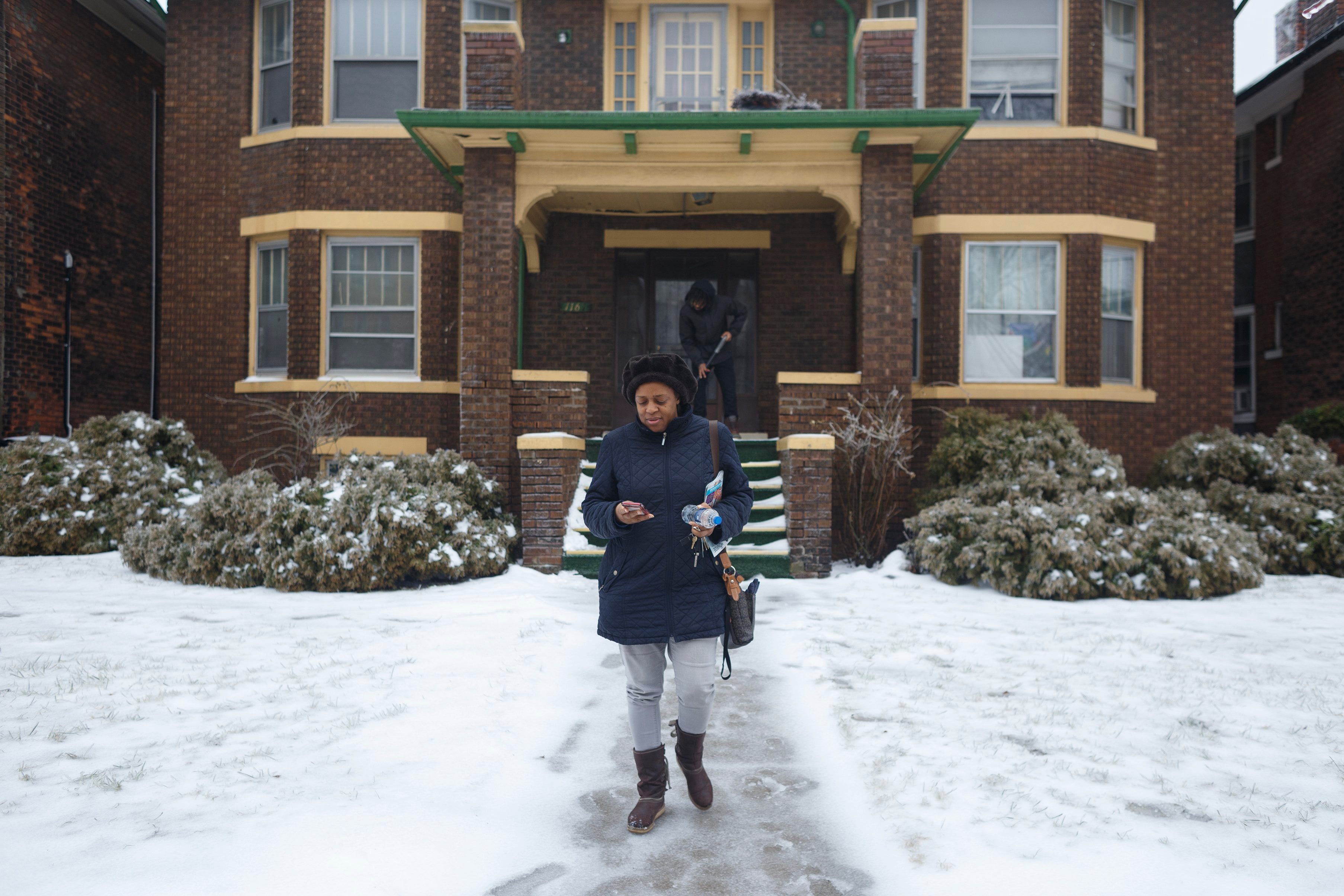 Charemon Brooks leaves her family home while her son Jalin Brooks shovels ice and snow from the front porch on Tuesday, Feb. 12, 2019 in Detroit. Charemon's home went into foreclosure and before she could buy it back, the house was sold to a developer. Brooks' two sons now live in the house and are unsure of their future.