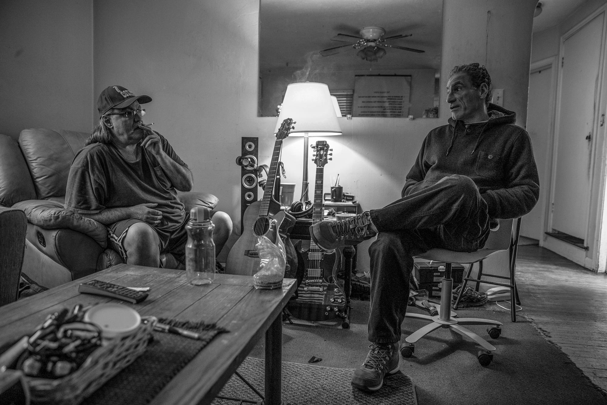 Ed Correll (left), a resident who lives in the halfway house in front of Pazzarelli's home, smokes a cigarette during an afternoon meeting in Indianapolis on Tuesday, Jan. 29, 2019.