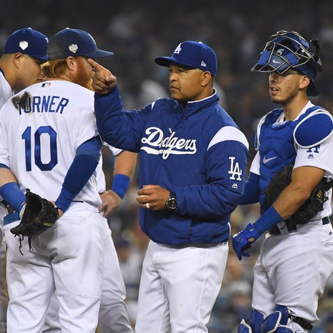 Dodgers manager Dave Roberts signals for a...