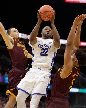Buffalo's Dontay Caruthers (22) drives to the basket between Central Michigan's Larry Austin Jr. (0) and Robert Montgomery (5) during the second half of an NCAA college basketball game in the semifinals of the Mid-American Conference men's tournament Friday, March 15, 2019, in Cleveland. Buffalo won 85-81.