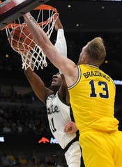Michigan State Spartans forward Aaron Henry (11)  dunks the ball as Michigan Wolverines forward Ignas Brazdeikis (13) defends him during the second half in the Big Ten conference tournament at United Center.