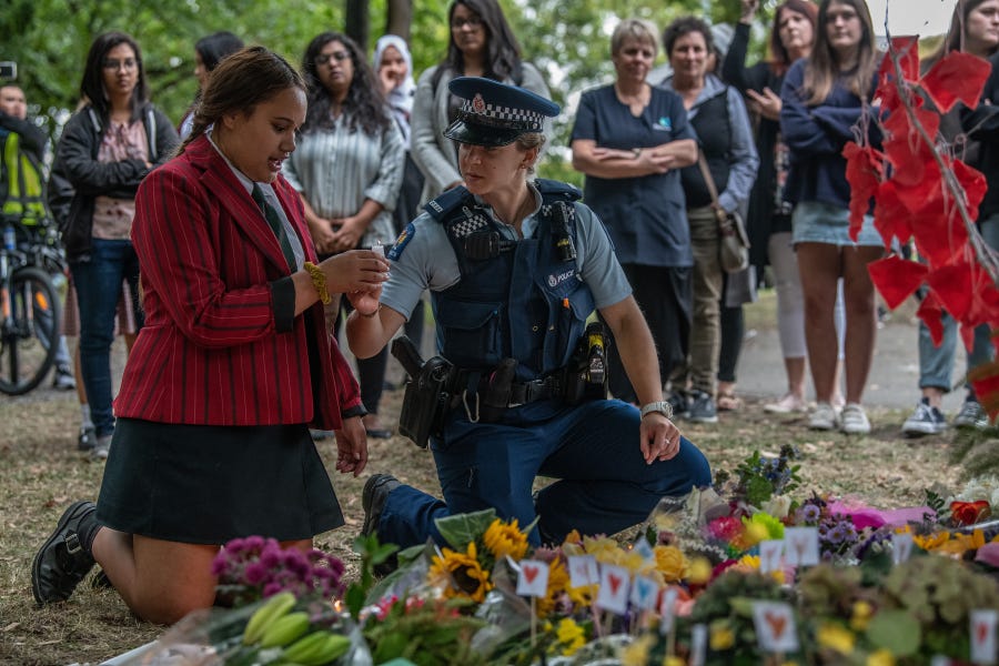 A police officer passes a candle to a schoolgirl during a students vigil near Al Noor mosque on March 18, 2019, in Christchurch, New Zealand.
