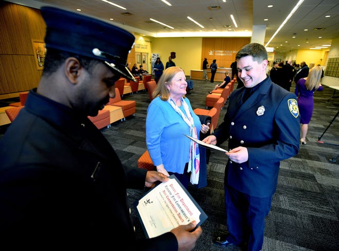 Firefighter Kenneth Durant and Thomas Haberstick look over the certificates they received for their life-saving actions in a March fire, with Haberstick's mother, Jennifer Haberstick, proudly looking on.