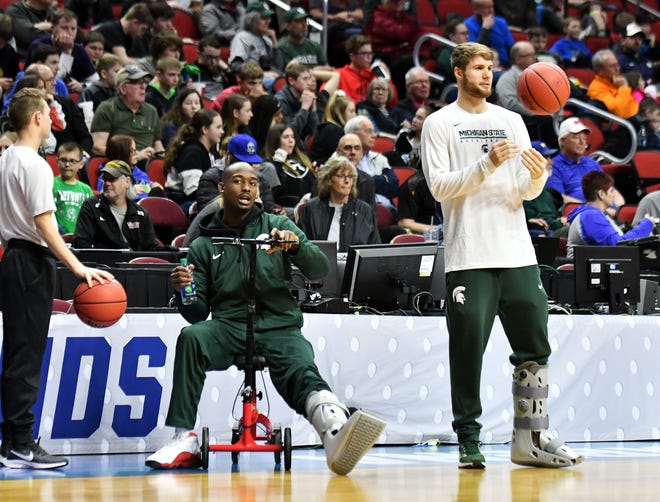 Two injured Spartans, Joshua Langford, left, and Kyle Ahrens, both wearing soft leg casts, watch their teammates practice Wednesday.