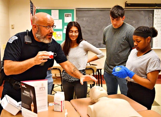 From left, York City School Police Officer Bryan Einsig, who is also the program director for York City Public Safety Academy, tells about each item in a Narcan kit while students Emily Vergara-Pimentel, Trey Bernstein, and Rayven Dickson look on during a demonstration about administering Narcan at York High School in York City, Thursday, March 21, 2019. Dawn J. Sagert photo