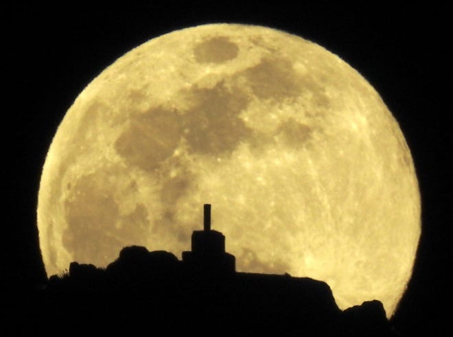 A full moon rises over Mount Pico Sacro near Santiago de Compostela, Spain.
