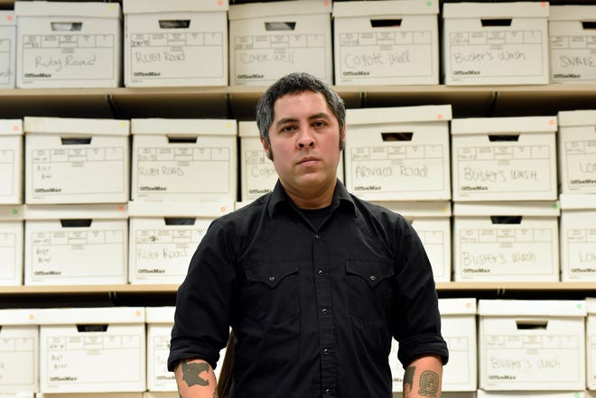 University of Michigan anthropologist Jason De León stands in his office with boxes of artifacts of things migrants left behind after crossing the Sonoran Desert.