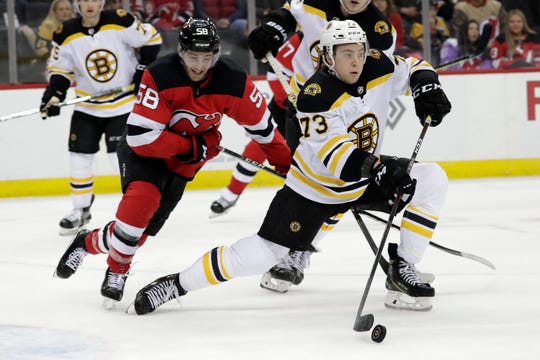 Boston Bruins defenseman Charlie McAvoy (73) stops a shot as New Jersey Devils center Kevin Rooney (58) watches during the second period of an NHL hockey game Thursday, March 21, 2019, in Newark, N.J.
