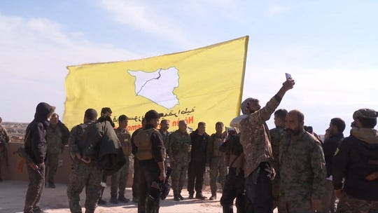 An image grab released by the Kurdish Ronahi TV on March 23, 2019 shows the US-backed Syrian Democratic Forces (SDF) raising their flag atop a building in the Islamic State group's bastion in the eastern Syrian village of Baghouz.