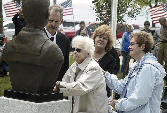 CORRECTS DATE - In this 2017 photo, Peg Ezdebski, surrounded by her children, looks at a bronze bust of her brother and Medal of Honor winner, William Charette, that was placed in the Veterans Memorial in Stearns Park, in Ludington, Mich. (Jeff Kiessel/Ludington Daily News via AP)