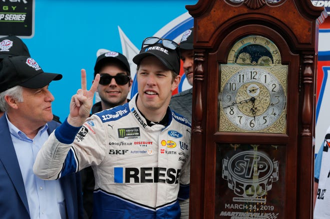 Brad Keselowski (2) celebrates with the trophy grandfather clock in Victory Lane after winning a NASCAR Cup Series auto race Sunday at Martinsville Speedway.