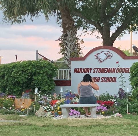 A woman sits Sunday at a sign for Marjory...