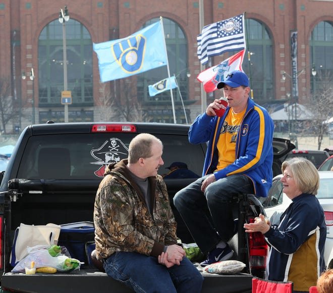 Glen Ross (from left) of Racine, Ryan Smoot of Pewaukee and Laree Allen of Fort Atkinson enjoy the warmer weather while tailgating on a tailgate before the game.