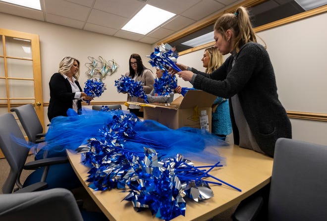 Staff members from the St. Clair County Child Abuse/Neglect Council work to bunch together blue pinwheels Thursday, March 28, 2019 in their downtown Port Huron office.