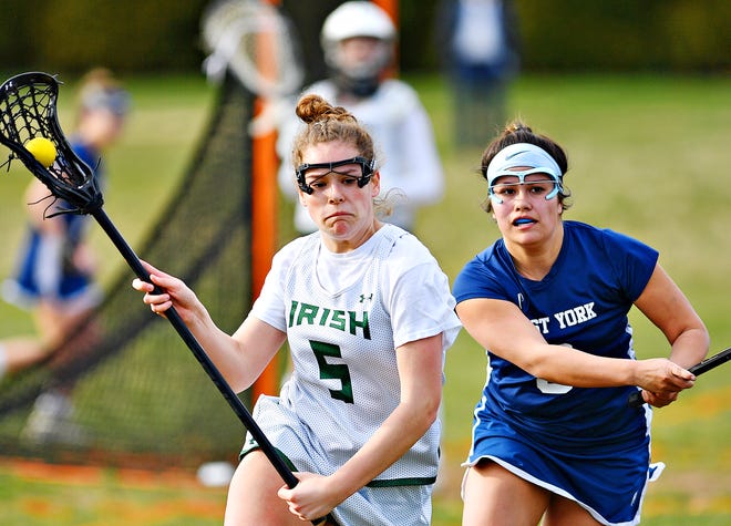 York Catholic's Grace Doyle, left, carries the ball while West York's Libby Bahoric during girls' lacrosse action at York Catholic High School in York City, Thursday, March 28, 2019. York Catholic would win the game 23-3. Dawn J. Sagert photo
