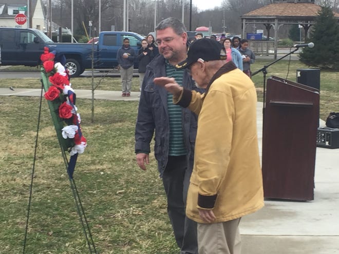After placing a wreath honoring Vietnam veterans on a stand, Vietnam veteran Harold Cheney Jr. salutes as Harold Cheney III looks on.