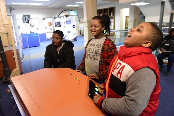 Educational games within the Discover NASA exhibit at the Mansfield/Richland County Public Library kept these three friends busy during Saturday's rainstorm. From left: Camryn Hood, 13; Kimaya Hood, 10; and Semaja Watts, 11. The extensive display gives children a complete experience of outer space, and will remain on the second floor of the library until May 30.