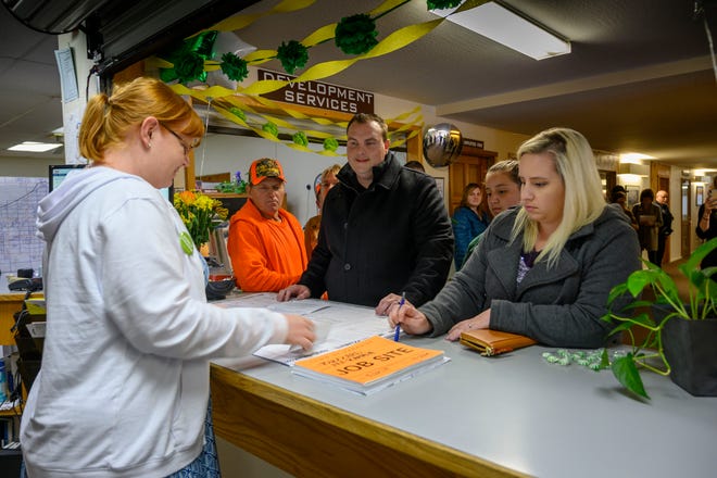 In this photo taken Thursday, March 28, 2019, Anne Vierra, with the town of Paradise, takes payment for the first building permit since the Camp Fire as Jason and Meagann Buzzard plan to rebuild their home in Paradise, Calif. Small signs of rebuilding a Northern California town destroyed by wildfire are sprouting this spring, including the issuing of the first permit to rebuild one of the 11,000 homes destroyed in Paradise five months ago. A city hall clerk on Thursday issued the couple a building permit to replace their home destroyed by the Nov. 8 fire that killed 85 people. The couple told reporters they never thought about leaving. Paradise Mayor Jody Jones said the Buzzards' permit is a sign that the town will rebuild.