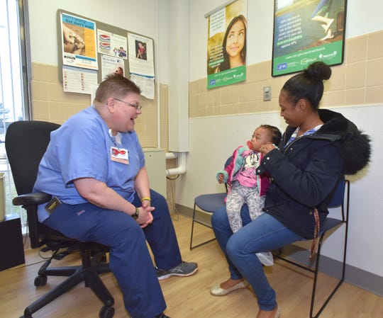 Nurse Jayne DeBoer-Rowse, left, chats with Royalty, a one-year-old girl, and her mother, Diamond Wilford, both of Oak Park, before the toddler receives a series. vaccinations, including one for MMR (measles, mumps and rubella). ) at the Oakland Health Center, Oakland County Health Division, Southfield.
