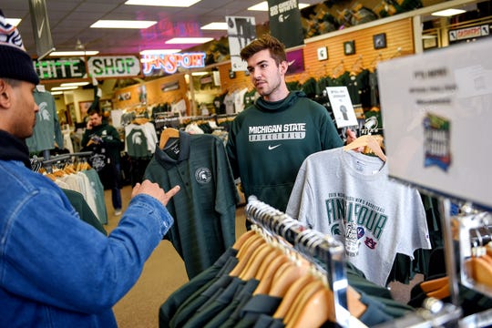 Michigan State University junior Garrett Brown, right, holds up two potential options as his friend and fellow junior Jordan Haber gives his input while the two shop for Final Four merchandise at the Student Book Store on Thursday, April 4, 2019, in East Lansing.