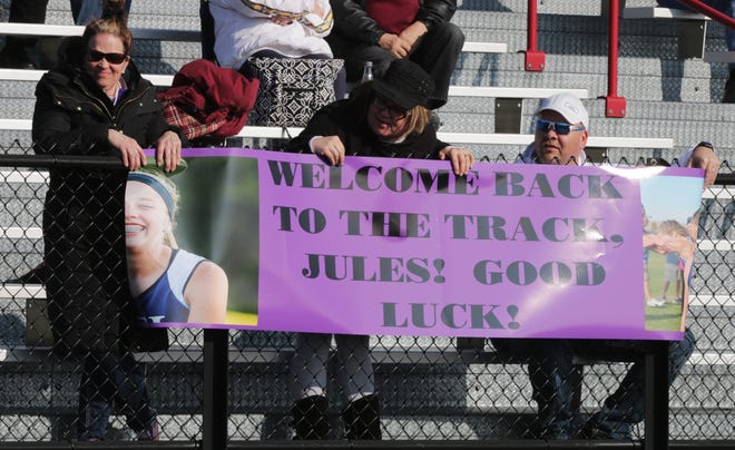 Family members of Julia Koenig proudly held a banner as Koenig ran her first event after being cleared to run following ACL surgery on April 5 in Oostburg.