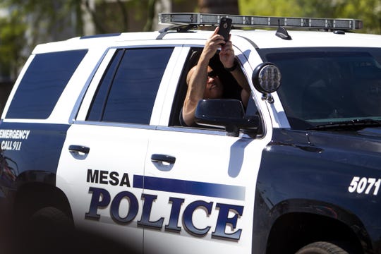 A Mesa police officer takes a photo from a squad car during the Phoenix Pride Parade on April 7, 2019.