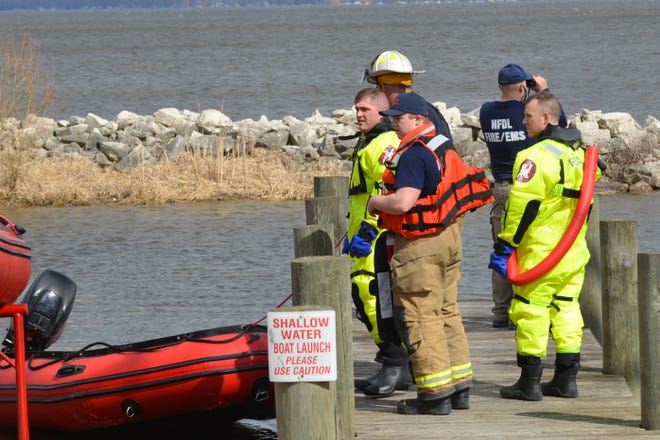 Crews stand near an inflatable boat on Lake Winnebago during a water rescue. A kayaker was stranded a mile from shore after overturning.
