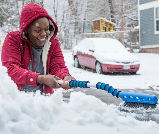 Penza Lemba clears the snow off her vehicle in Lewiston, Maine, on Monday, April 8, 2019, as snow piled up overnight. While New England digs out from one storm, a blizzard is bearing down on the north-central U.S.