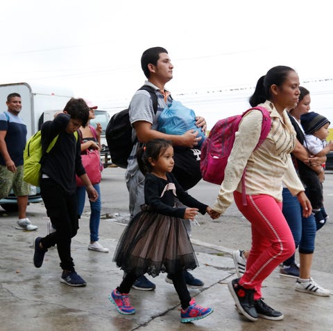 Migrants walk along a highway as a new caravan of...