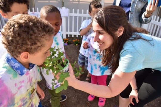 20029124A Kathleen Moran of the Binder Autism Center offers the smell of a mint chocolate plant to Alex Camilo at the garden of St. Joseph’s Wayne Hospital on Tuesday. Binder Autism Center clinicians are using gardening as the vehicle to teach and practice social skills to children affected with autism