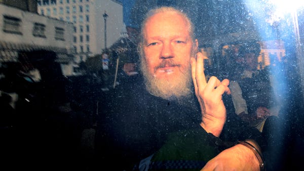 Julian Assange gestures to the media from a...