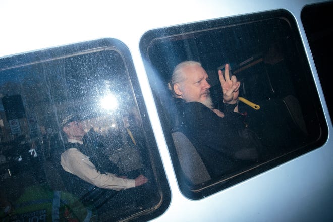 Julian Assange gestures to the media from a police vehicle on his arrival at court on April 11, 2019 in London, England.