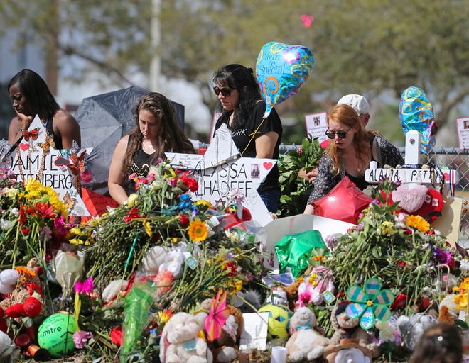 Mourners bring flowers on Feb. 25, 2018, as they pay tribute at a memorial for the victims of the shooting at Marjory Stoneman Douglas High School, in Parkland, Fla.