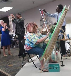 Artist Joan Crutcher, seated, works on a painting during a service at Unity of Melbourne.