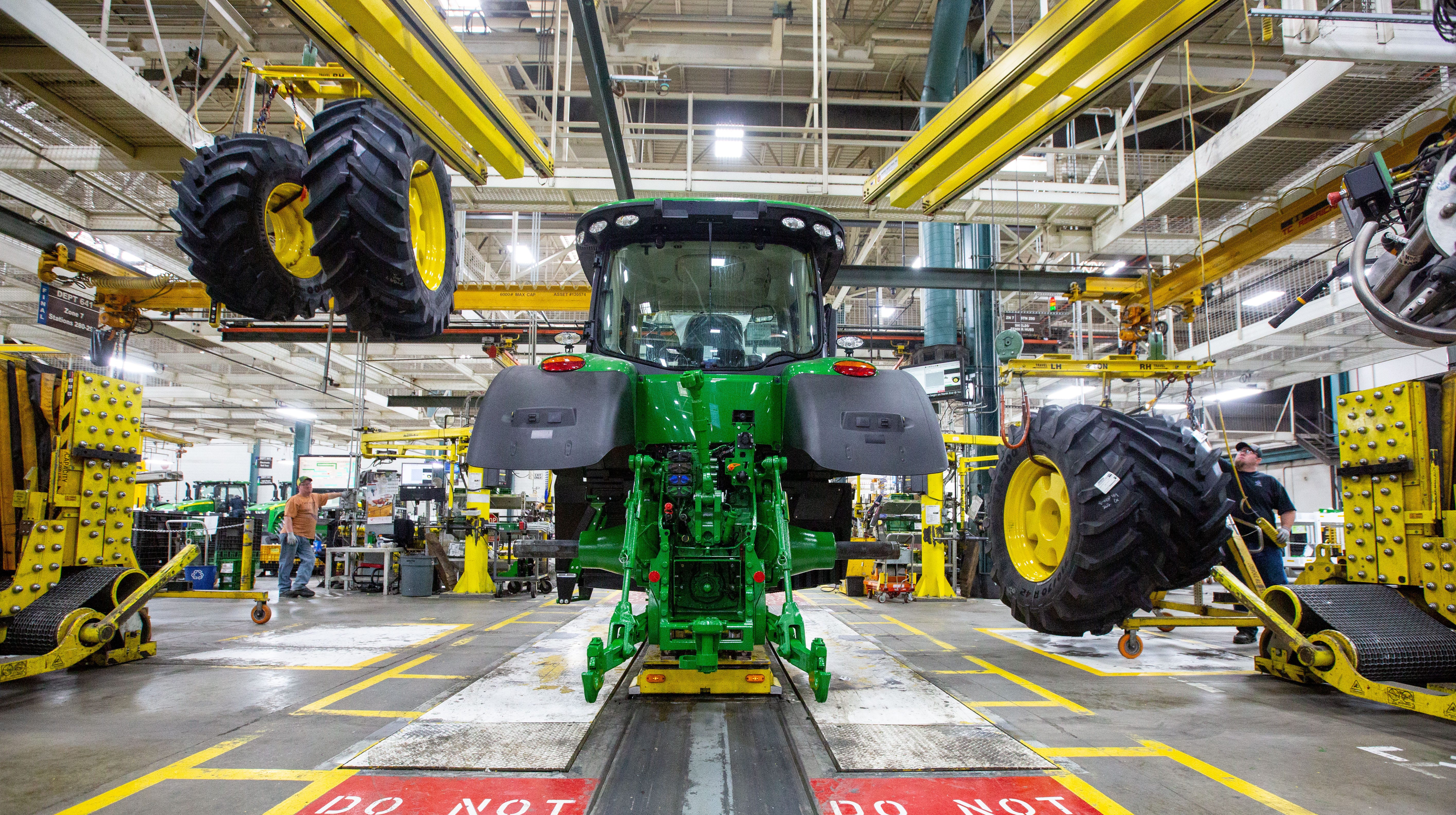 Wheels drop down from above as workers assemble a tractor at John Deere's Waterloo assembly plant.