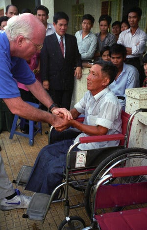 Sen. Patrick Leahy, D-Vt., in 1996,  shakes hands with a Vietnamese man injured by a landmine gets who received his first wheelchair at a clinic in Vietnam funded through the Leahy War Victims Fund.