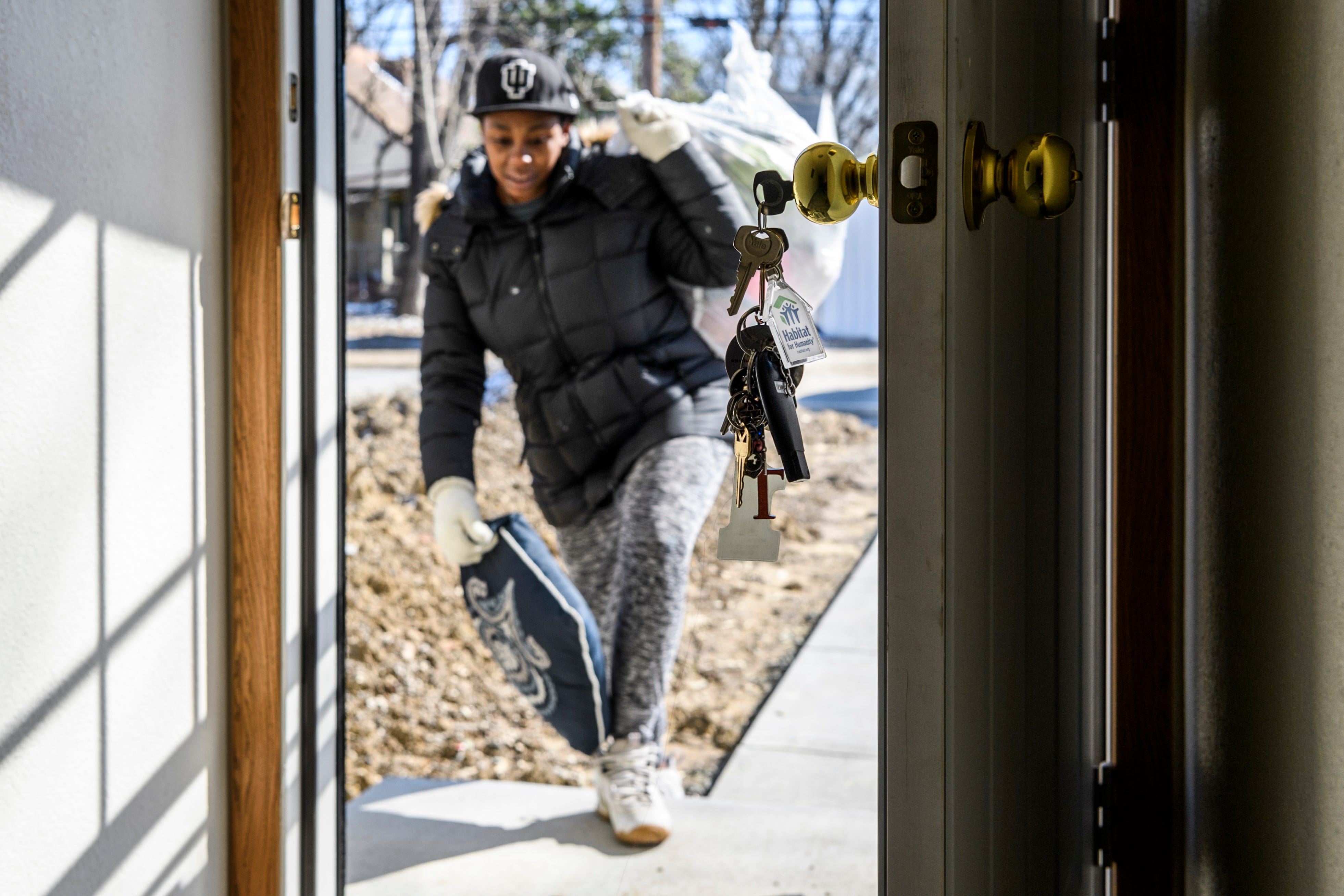 Keys featuring a house-shaped keychain with the Habitat for Humanity logo dangle from the back door as Tamisha Dilworth carries a pillow and a bag full of clothes into her new house, Monday morning, March 4, 2019. She promptly began moving her family's items into their new space after signing paperwork and receiving the keys. 