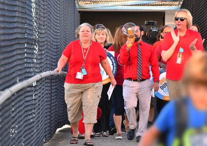  A couple of dozen teachers, most wearing red T-shirts and chanting "red for ed" did a walk in to school at Fairglen Elementary School in Sharpes to bring awareness to the need for for funding for schools. Anthony Colucci, president of the Brevard Ferderation of Teachers, used a bullhorn to lead the chant as teachers, media and students used the raised walk over to cross over US 1. 