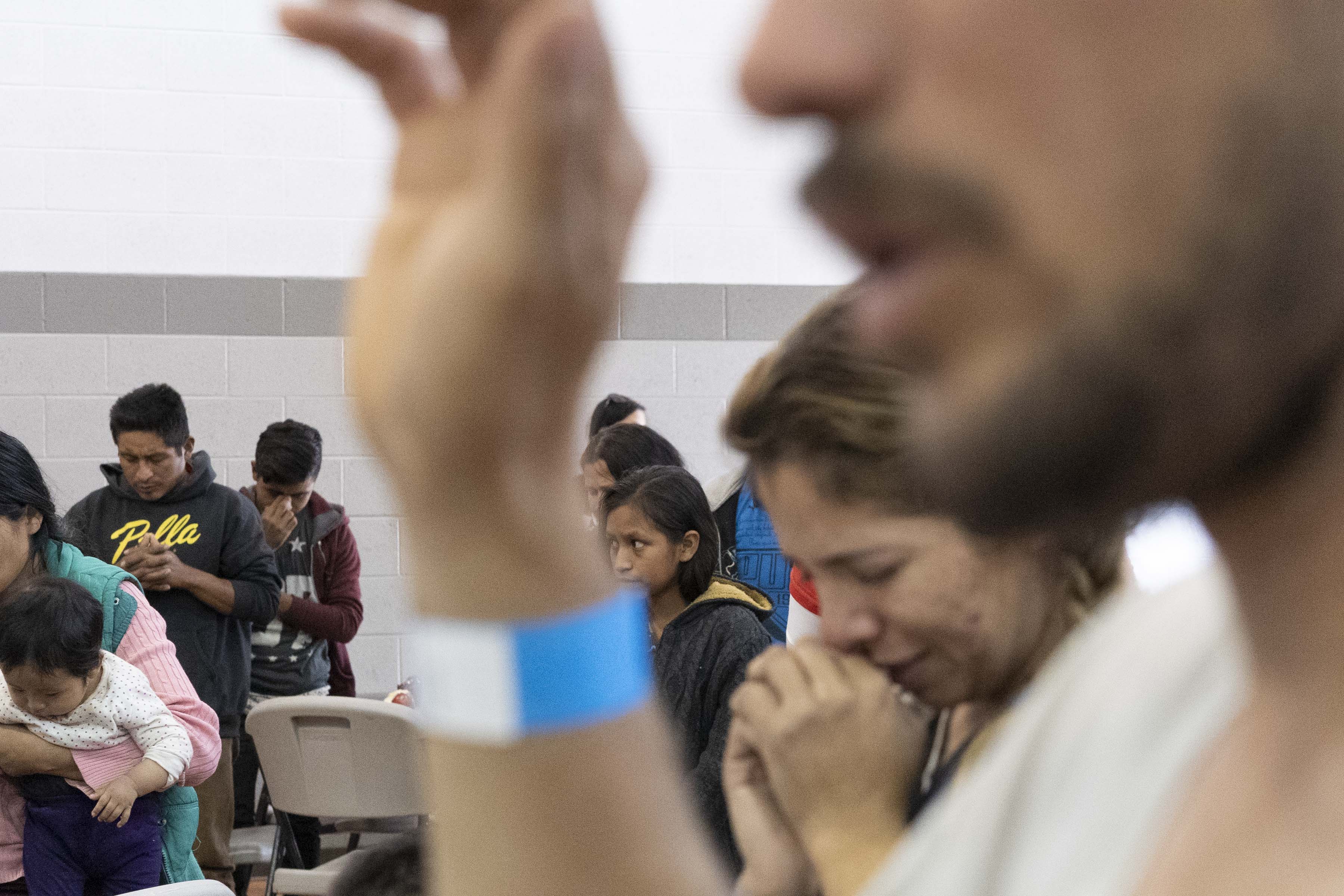 Central American migrants pray with hosts at the Vineyard Community Church.