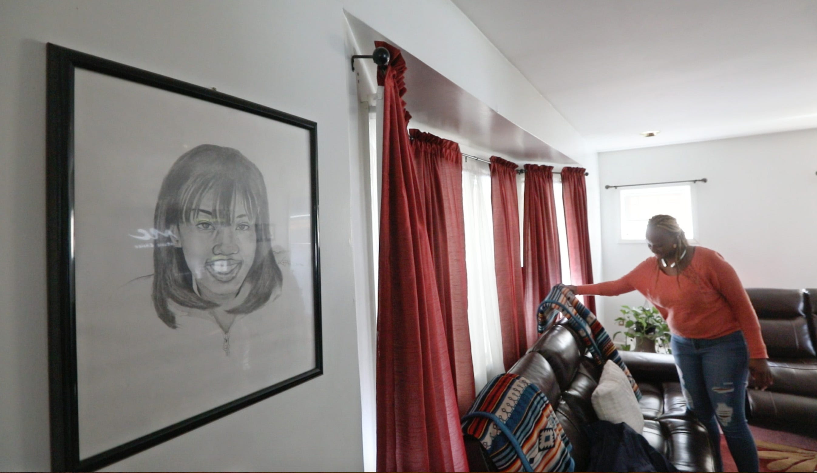 Tawana Wyatt, mother of India Cummings, straightens her living room as a portrait of India looks over her in her Rochester home Friday, March 1, 2019.