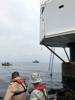 Thai naval officers inspecting a a floating dwelling in the Andaman Sea.