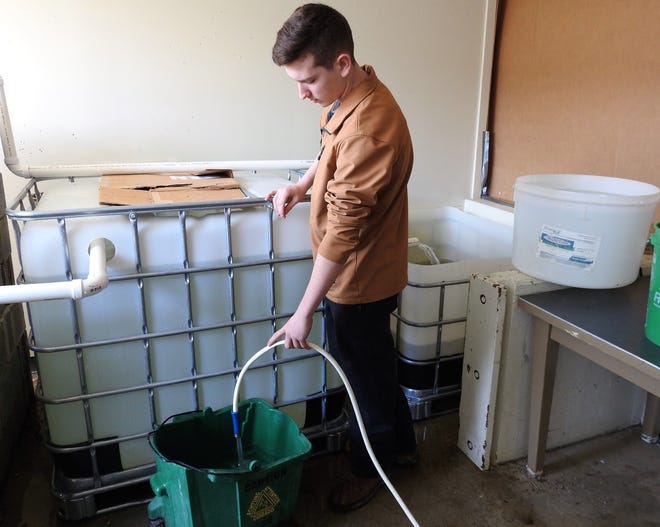 Junior Caleb Dille of the Coshoton County Career Center fills containers with water to sit overnight before being added to the aquaponics garden. Fish waste is circulated to a grow bed of pea gravel for lettuce. Water with nitrogen fixating bacteria then goes from the garden back to the fish tank.