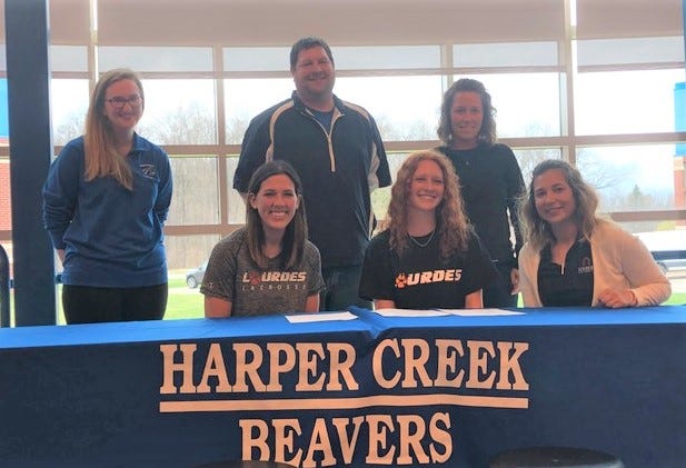 Harper Creek's Ashton Rowe signed to play lacrosse at Lourdes University in Ohio. She is joined by her high school lacrosse coaches and her parents.
