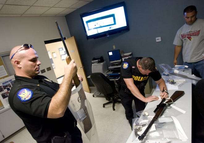 Phoenix Police Officer Tim Baiardi (left) impounds a firearm that was surrendered at the Phoenix Police Department Maryvale precinct on Sat., June 13, 2009.